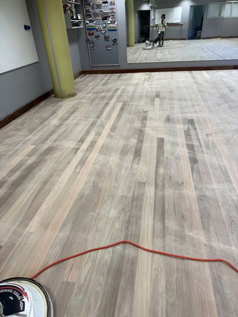 Floorboard restoration in progress at Freshwater Senior Campus, with sanding equipment visible in the room reflection